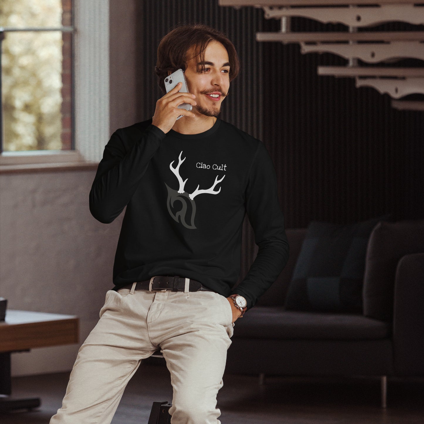 Male model talking on cellphone wearing Ciao Cult Antler Holiday Special Edition Long Sleeve Fitted Crew in black.