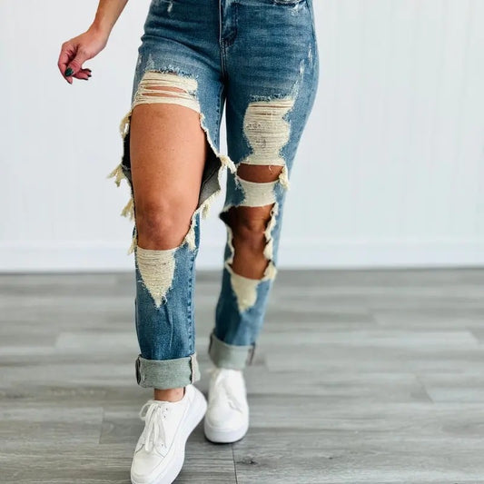 Close-up of Ciao Cult Women’s High-Waist Ripped Straight-Leg Jeans, model lifting right leg to show thigh and ripped knee detail.