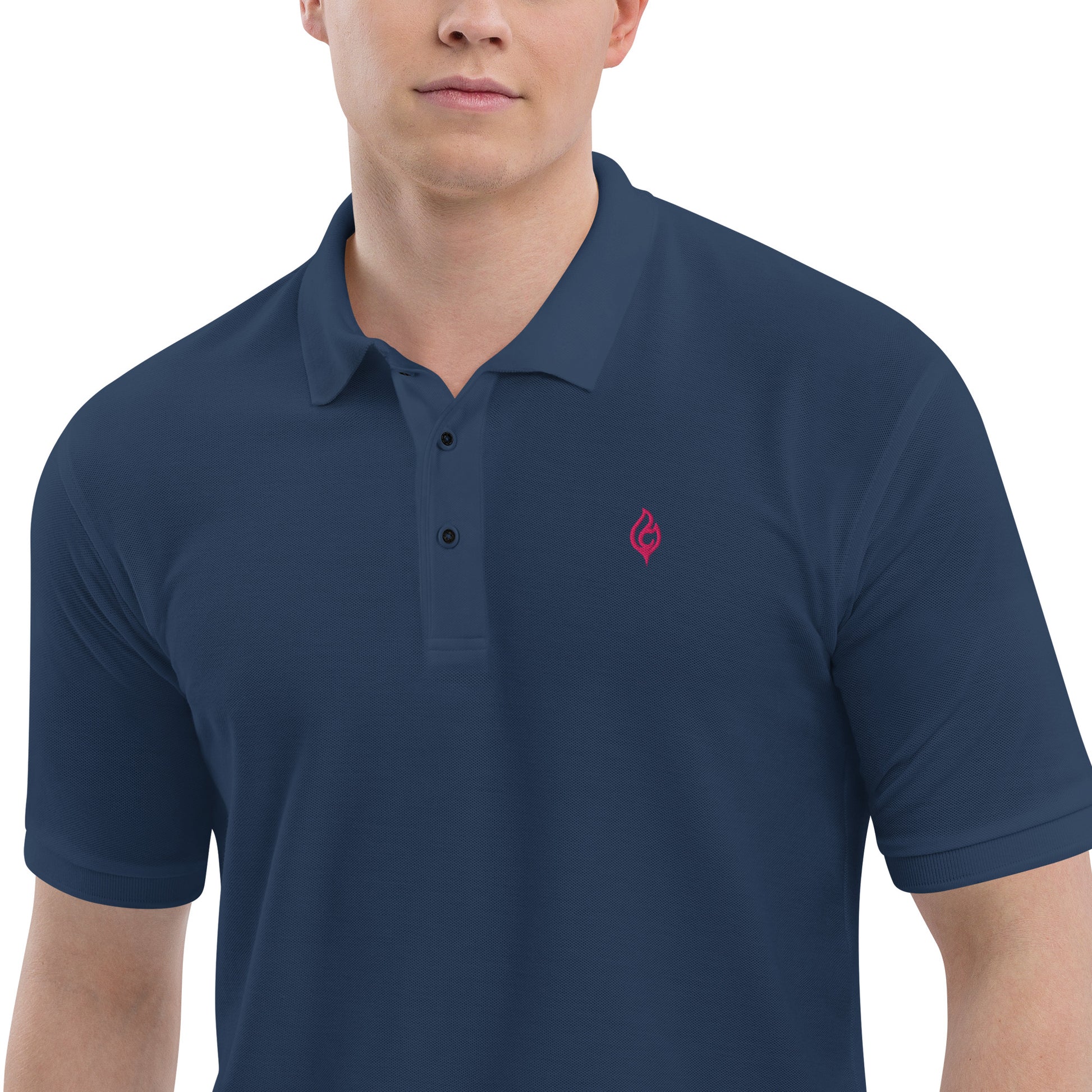 Close-up waist-to-jaw view of male model wearing Ciao Cult Men’s Signature Flame Polo in navy with flamingo-pink flame emblem.