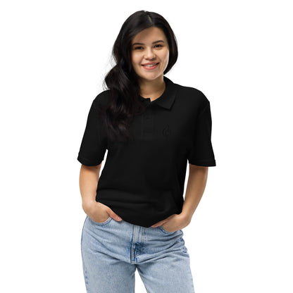 Female model smiling front view wearing Ciao Cult Tonal Black-on-Black Signature Flame Polo with jeans, hands in pockets, relaxed pose.